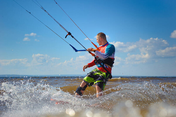 Kiteboarding. A young man kitesurfer enjoys riding the waves on a kite.