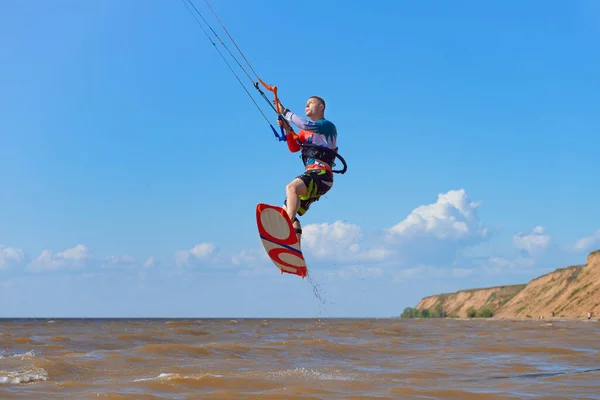 キーボードだ 若い男のカイトサーファーは凧に波に乗るのを楽しんでいます 男はサーフボードでトリックジャンプを実行します — ストック写真