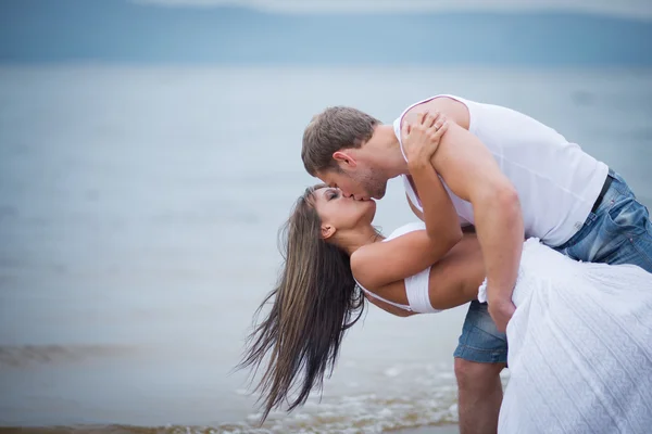 Joyeux jeune couple amoureux marchant sur la plage — Photo