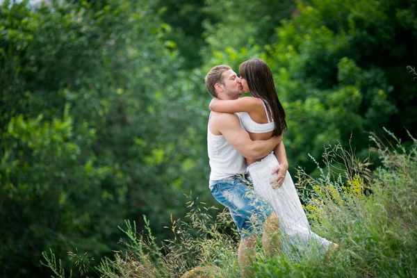 快乐的年轻夫妇，在爱走在一片草地 — 图库照片