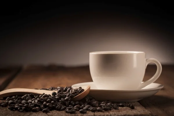 Кавові зерна та чашка кави на дерев'яному столі — стокове фото