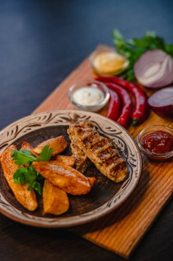 Patates dilimli ızgara tavuk ve ahşap tabakta çeşitli baharatlar..