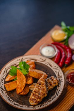 Kızarmış tavuk ve kızarmış patates, kırmızı biberli ve soslu kırsal tabakta..