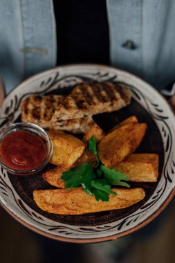 Patates dilimli ızgara tavuk ve seramik tabakta sos..