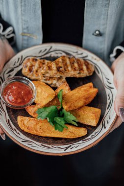 Dekoratif tabakta domates soslu ızgara tavuk ve patates..