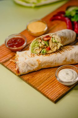 Tahtada salata, domates, sos ve biberli taze tavuk dürümü..