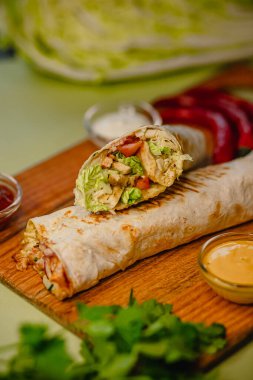 Tahtanın üzerinde taze sebzeler ve nefis tavuk dürümü..