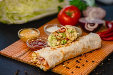 Tahtada taze sebze ve sosla ızgara tavuk dürümü..