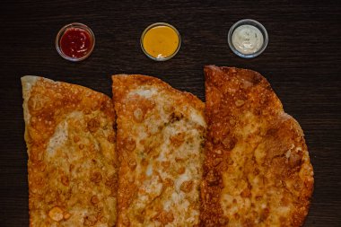 Koyu ahşap arka planda çeşitli soslu kızarmış hamur işleri..