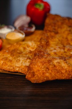 Ahşap masada taze kırmızı biber ve soslu kızarmış hamur işi..