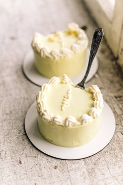 Kırsal yüzeyde kremalı kıvrımları olan zarif beyaz kremalı mini kekler..