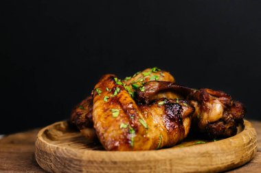 Ahşap tabakta otlarla süslenmiş lezzetli ızgara tavuk kanatları..