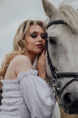 Beyaz atı kucaklayan beyaz atlı genç beyaz kadın..