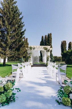 Açık havada, açık mavi gökyüzünün altında çiçeklerle süslenmiş güzel bir düğün töreni..