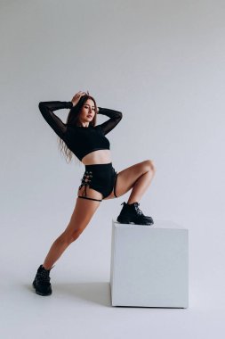 Siyah kıyafetli özgüvenli dansçı stüdyo ortamında poz veriyor..