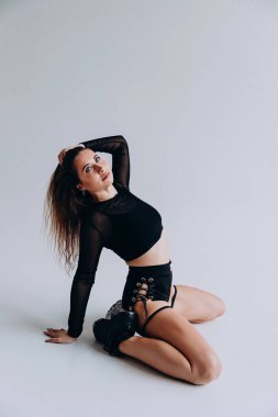 Modern dans pozu veren kadın şık siyah elbiseler ve şeffaf kollar giyiyor..