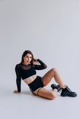 Tarafsız bir arkaplanda poz veren siyah örgülü bir kadın..