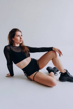 Siyah elbiseli atletik kadın beyaz arka planda poz veriyor..