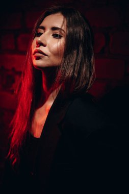 Moda tasarımı için tuğla duvara çarpan kırmızı ışıklandırmalı kadın..
