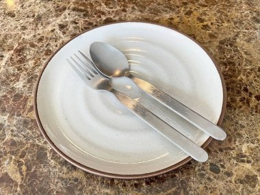 Masadaki beyaz seramik tabakta çatal ve kaşık