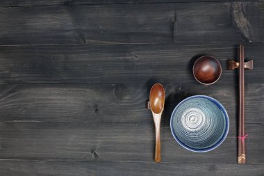 Çin, Japon, Kore ve Asya yemekleri için ahşap zemin üzerinde yemek çubukları, kaşık ve kase, fotokopi alanı ile üst görünüm                               