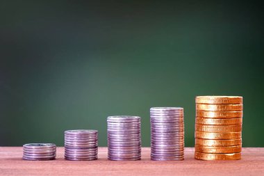 Dört gümüş para yığını ve büyüyen istikamette büyüyen bir yığın altın para, finans, işletme, muhasebe, finans, kredi ve faiz, Kâr, Yatırım kavramları için yeşil doğa arka planı