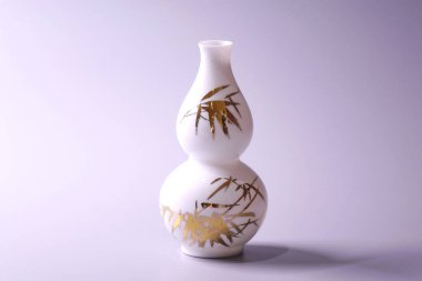 Gri arkaplan üzerine antik Çin yumurta kabuğu porselen vazosu. Beyaz porselen vazodaki altın bambu yaprakları, Çin 'in ünlü antik Ming ve Qing hanedanlığı çömlekleri.