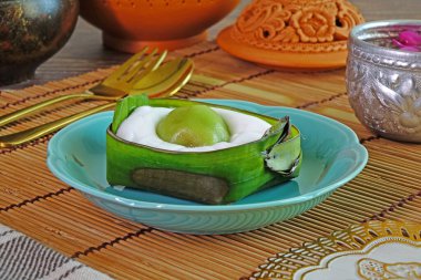 Tayland tatlısı: Hindistan cevizi kremalı ve yeşil pandan aromalı pirinç unlu taze yeşil muz yaprağına sarılı (Khanom Sod Sai Sawei), seçici odaklı.
