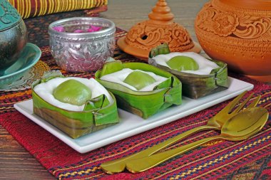 Tayland tatlısı: Hindistan cevizi kremalı ve yeşil pandan aromalı pirinç unlu taze yeşil muz yaprağına sarılı (Khanom Sod Sai Sawei), seçici odaklı.
