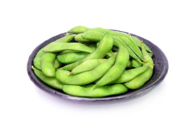 Japon siyah toprak kaplamasında beyaz arka planda izole edilmiş fasulye fasulyesi. Buharda pişirilmiş soya fasulyesi, Japon mutfağının popüler mezesi..