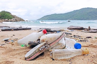 Kirlilik: Deniz plajı kirliliği. Plajda terlikler, cam ve plastik şişeler. Seçici odak ve kopyalama alanı