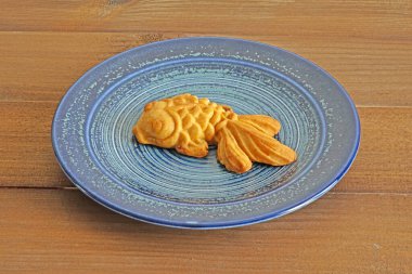 Japon balığı şeklinde çay bardağıyla mavi tabakta Çin ay çöreği. Sonbahar ortası festivali için ay çöreği, Çin geleneksel pastası.