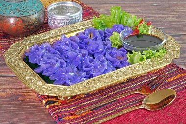 Royal Thai cuisine : Purple blue color Flower-shaped Thai dumpling (Khanom Chor Muang) Famous ancient Thai appetizers.(Purple blue color from the Asian pigeon wings flower, Butterfly, or Darwin pea) clipart