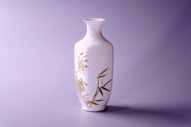Gri arkaplan üzerine antik Çin yumurta kabuğu porselen vazosu. Beyaz porselen vazodaki altın bambu yaprakları, Çin 'in ünlü antik Ming ve Qing hanedanlığı çömlekleri.
