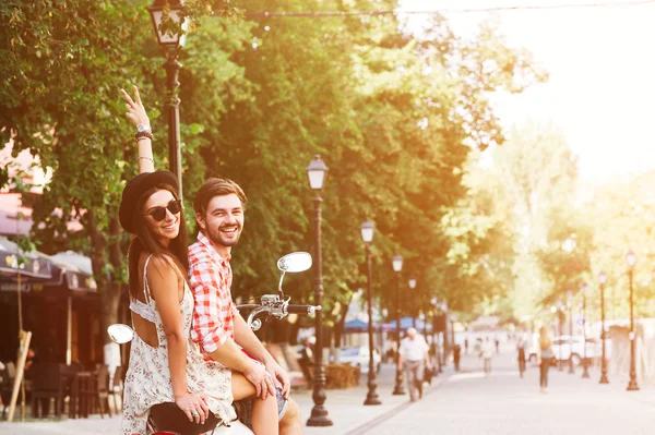 Pareja joven montando un scooter vintage en la calle — Foto de Stock