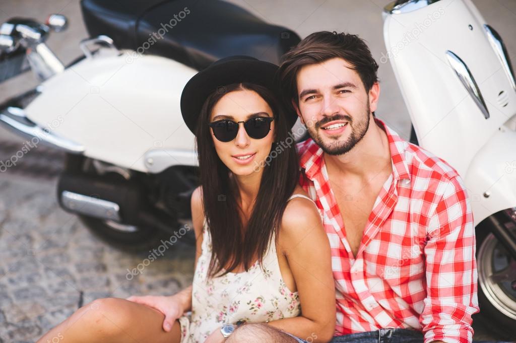 couple sitting near retro scooter
