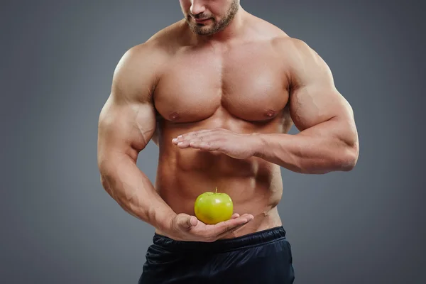 Construtor de corpo sem camisa segurando uma maçã — Fotografia de Stock