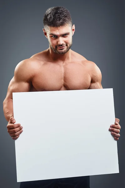 Fisiculturista com cartaz branco em branco — Fotografia de Stock