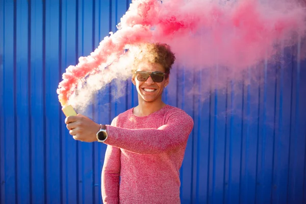 Menino segurando uma fumaça rosa colorida — Fotografia de Stock