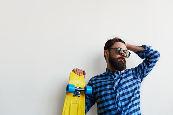 bearded hipster holding yellow skateboard