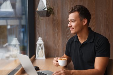 Bir fincan kahve ile kafede oturan genç yakışıklı adam