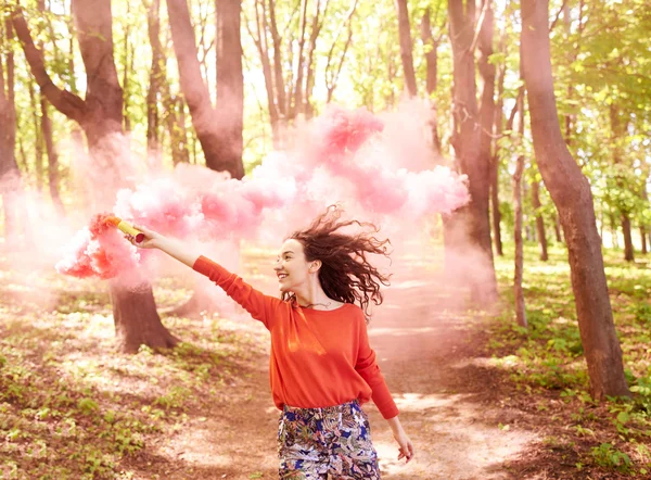 Ευτυχισμένος κορίτσι γελώντας και τρέχοντας με ροζ χρώμα βόμβα καπνού στο δάσος. — Φωτογραφία Αρχείου