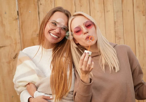 Mulheres alegres soprando bolhas juntas — Fotografia de Stock