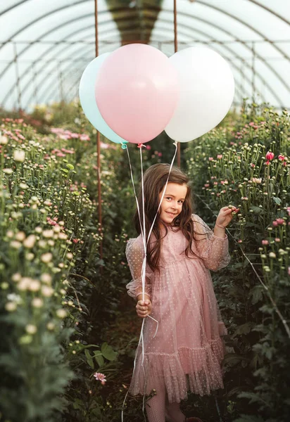 Menina bonito com balões em estufa — Fotografia de Stock