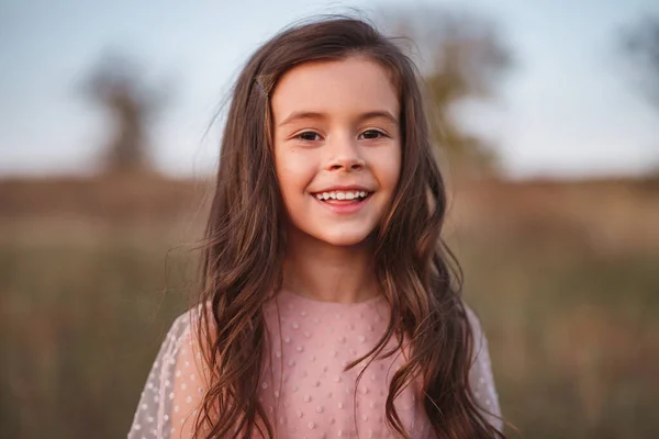 Usmívající se holčička stojí v poli — Stock fotografie