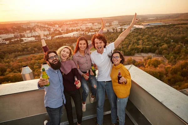 Радісні друзі з напоями, що збираються на даху — стокове фото