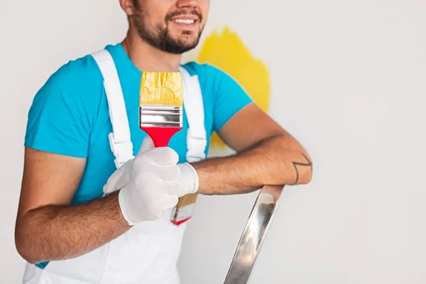 Crop worker on ladder showing brush with paint — Stock Photo, Image