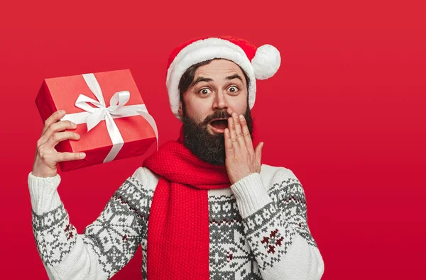 Homem barbudo chocado mostrando presente de Natal — Fotografia de Stock