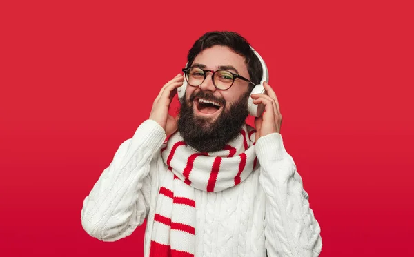 Glada man i vinter tröja och halsduk njuter av musik med hörlurar — Stockfoto