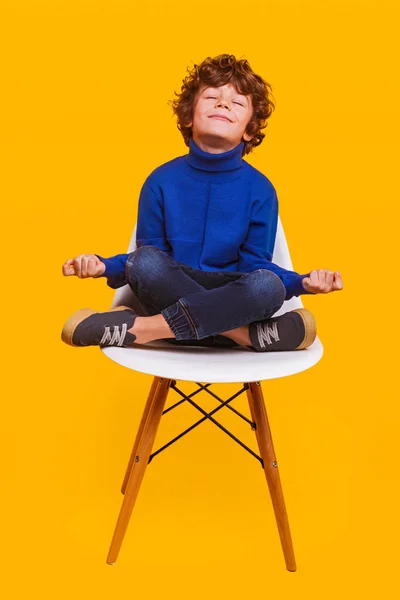 Gelukkige jongen mediteren op stoel — Stockfoto